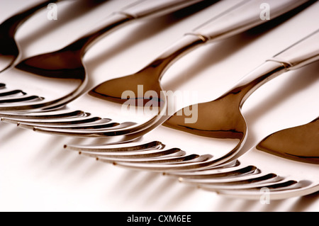 Fila di acciaio inossidabile forche su sfondo bianco Foto Stock