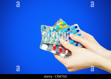 Pillole di capsule di antibiotico in mano isolato su blu Foto Stock
