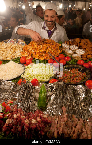 Waither locale/chef in stallo alimentare al mercato notturno in Djemaa el Fna Squre a Marrakech in Marocco. Foto Stock