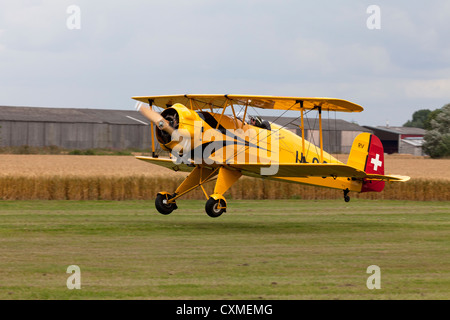 Bucker Bu 133C Jungmeister U-99 RV G-AXMT atterraggio su pista in erba Foto Stock