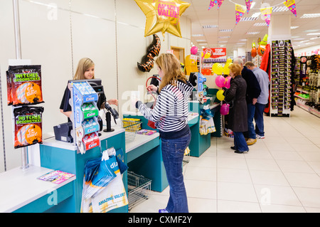 I clienti sono serviti presso la cassa in un Poundland shop store. Foto Stock