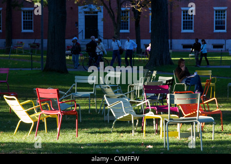 Colorate sedie attendere per stancare gli studenti e turisti, nel sole in Harvard Yard, il cuore antico della Harvard University. Foto Stock