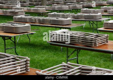 Tavoli e sedie impilate ordinatamente su un prato a Harvard Yard in attesa per le persone per il loro utilizzo in corrispondenza di un evento. Foto Stock