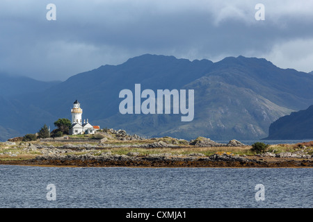 Tradizionale vecchio faro sull isola Ornsay a Skye con montagne sulla terraferma scozzese al di là. Foto Stock
