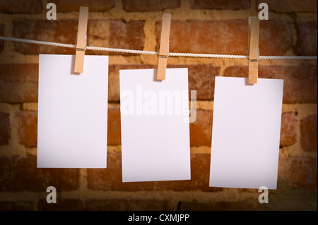 Una fila di cinque note vuote su stendibiancheria di fronte a un muro di mattoni, con spazio di copia Foto Stock