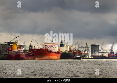 Le petroliere in porto con rainclouds, sole e background industriale Foto Stock