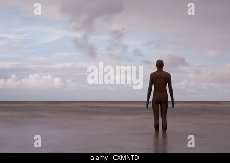 Un lungo giorno di esposizione immagine luminosa di uno di Anthony Gormley la ghisa sculture rivolta verso l'orizzonte su Crosby beach Foto Stock