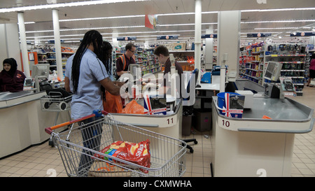 Gli acquirenti di pagare e carrello di carico alla cassa shopping in Sainsbury's supermercato Walthamstow Londra Inghilterra KATHY DEWITT Foto Stock