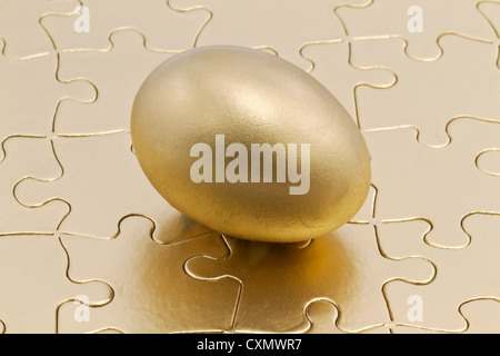 Golden Nest uova siede su oro metallizzato puzzle; risparmio è la chiave per la finanziaria e business puzzle. Foto Stock