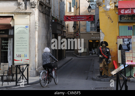 Donna su una bicicletta attraverso le strade della città vecchia, Arles, Camargue, Francia, Europa Foto Stock