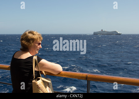 La donna gode di vista sul mare dalle rotaie della Cunard liner "Queen Victoria" cercando di fronte alla nave gemella "Queen Elizabeth" Foto Stock
