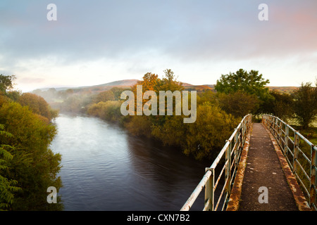 Passerella a piedi per gli amanti del ferro con vista sul fiume degli alberi autunnali sul fiume Ure vicino ad Asygarth, North Yorkshire Dales e National Park, Regno Unito Foto Stock