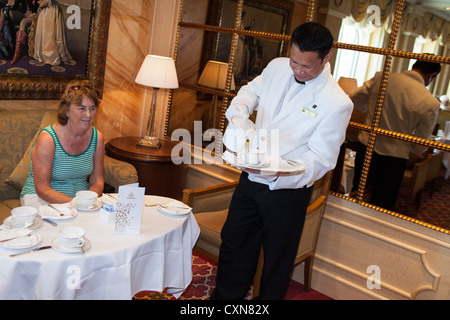 Gustando il tè del pomeriggio. Servire il tè del pomeriggio nel Queens Room. Cunard Liner "Queen Victoria" in mare. Steward versando una tazza di tè. Foto Stock