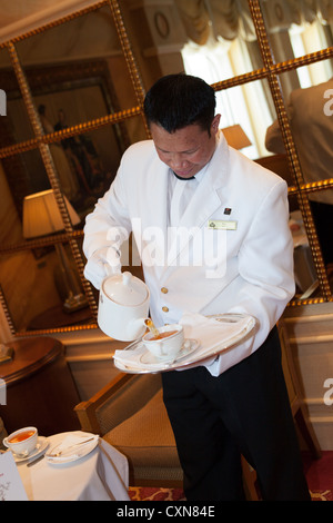 Gustando il tè del pomeriggio. Servire il tè del pomeriggio nel Queens Room. Cunard Liner "Queen Victoria" in mare. Steward versando una tazza di tè. Foto Stock