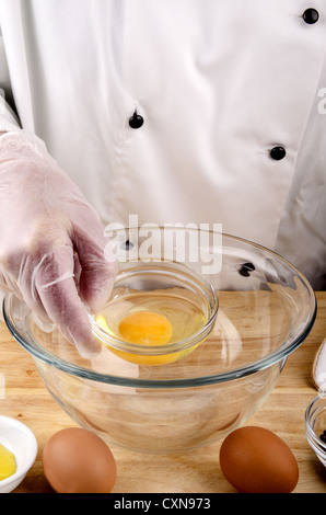 Lo chef femmina ha un uovo in una piccola ciotola per preparare la maionese Foto Stock