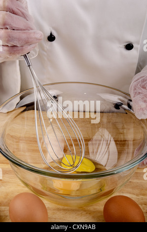 Lo chef femmina in uniforme tenendo una frusta Foto Stock