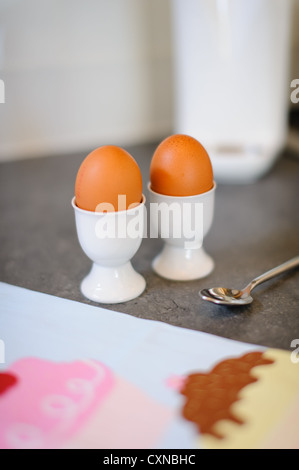 Due uova uovo in tazze su un piano di lavoro di una cucina Foto Stock