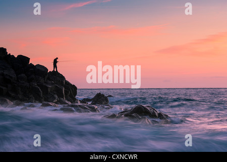 Un pescatore che cattura l'ultima luce sulla porta Nanven sulla costa nord della Cornovaglia, Inghilterra Foto Stock