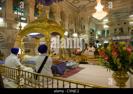 I sacerdoti nel corridoio principale di preghiera del Gurudwara Sis Ganj Sahib, un tempio sikh in Chandni Chowk, Vecchia Delhi, India Foto Stock