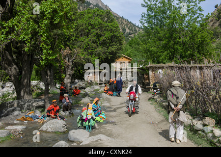 Kalash ragazze vestiti di lavaggio in un flusso a Balangur Village, Rumbur Valley, biglietto, Pakistan Foto Stock