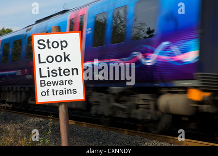 Treno in movimento e segno, dall attraversamento pedonale sulla linea ferroviaria, avviso di persone sui treni Foto Stock