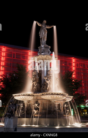 Tyler Davidson genio della fontana in Piazza Fontana, Cincinnati a notte con rosso edificio illuminato Foto Stock
