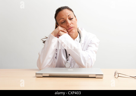 Medico donna dorme da scrivania da ufficio Foto Stock