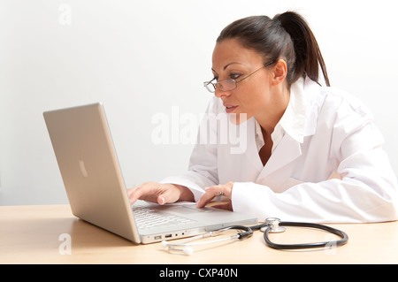 Medico donna utilizzando computer laptop sulla scrivania in ufficio Foto Stock