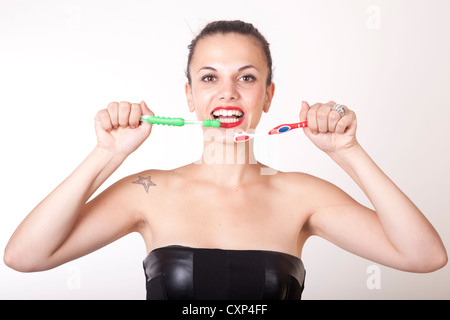 Ritratto di una giovane donna bella pulizia i suoi denti con gli spazzolini da denti. Foto Stock