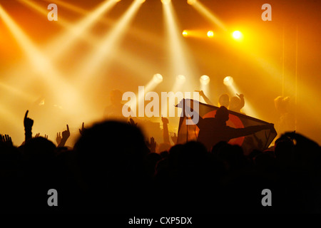 Stagliano spettatori / folla e un ambiente live durante un concerto rock con i bilancieri sul palco illuminato da faretti Foto Stock