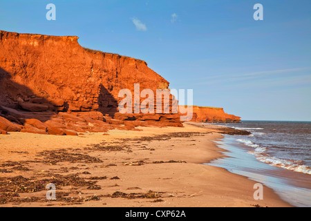 La luce del mattino colpisce le scogliere di arenaria e la spiaggia sul lato nord di Prince Edward Island, Canada. Foto Stock