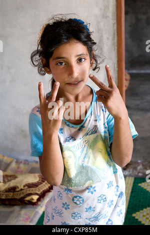 Un bambino siriano rifugiato tiene le dita sul segno della vittoria, nella regione di Wadi Khaled nel nord del Libano, vicino al confine con la Siria. Foto Stock