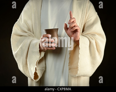 Gesù mani coppa di vino isolato su sfondo scuro Foto Stock