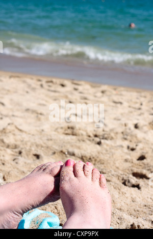 Coperto di sabbia piedi femmina su una spiaggia Foto Stock