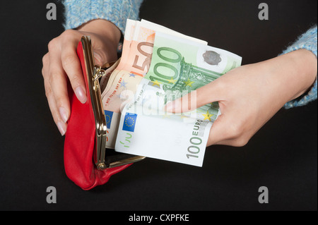 Donna di mani portamonete rosso contenente alta denominazione delle banconote in euro Foto Stock