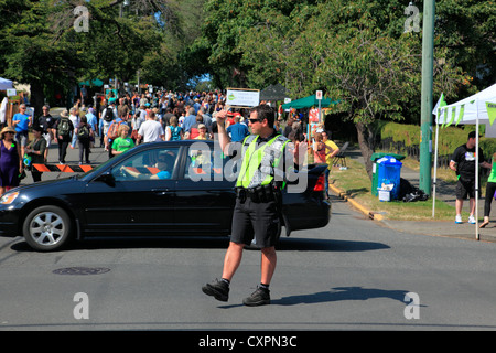 Poliziotto che dirige il traffico a una strada che attraversa la Moss street art show e la vendita in Victoria BC Canada Foto Stock