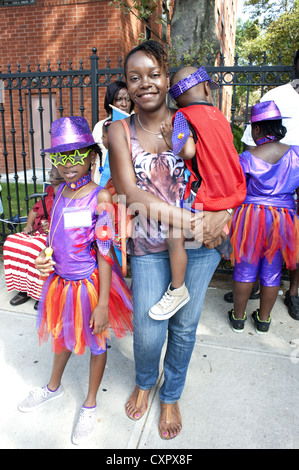 USA: Brooklyn, New York. La madre ed i suoi due bambini in costume attendere a marzo nei Caraibi Kiddies parata del giorno, 2012. Foto Stock