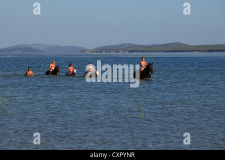 Giovane donna e tre bambini a cavallo nelle acque di Vransko jezero (Lago di Vrana) vicino a Pakostane, Croazia. Foto Stock