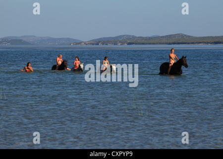 Giovane donna e tre bambini a cavallo nelle acque di Vransko jezero (Lago di Vrana) vicino a Pakostane, Croazia. Foto Stock