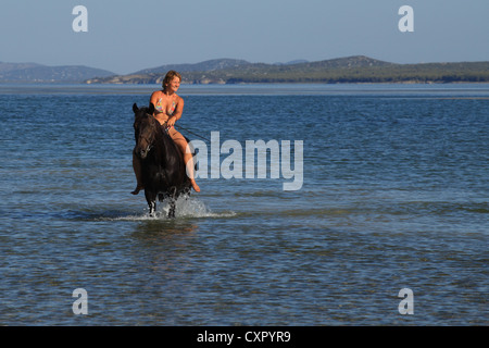 Giovane donna a cavallo nelle acque di Vransko jezero (Lago di Vrana) vicino a Pakostane, Croazia. Foto Stock