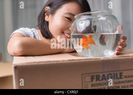 Giovane donna guardando goldfish sulla scatola di movimentazione Foto Stock