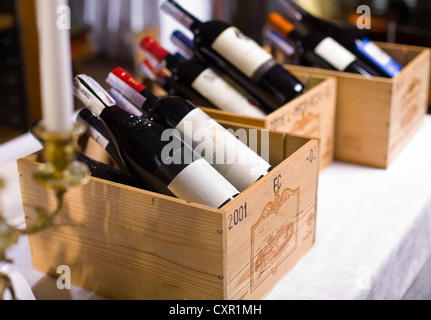 Le bottiglie di vino in scatole di legno sono sul tavolo del ristorante. Foto Stock