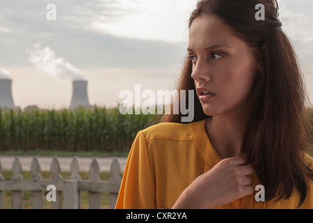 Malinconici donna che guarda lontano con la centrale nucleare in background Foto Stock