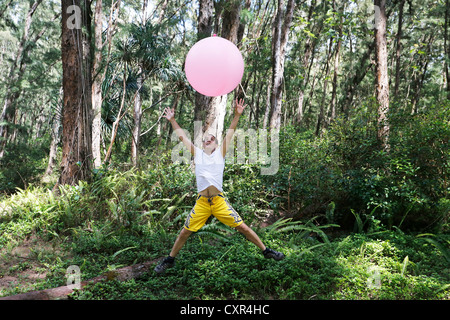 Uomo con un palloncino nei boschi, la leggerezza e la libertà, Nanawale colline, Big Island, Hawaii, STATI UNITI D'AMERICA Foto Stock