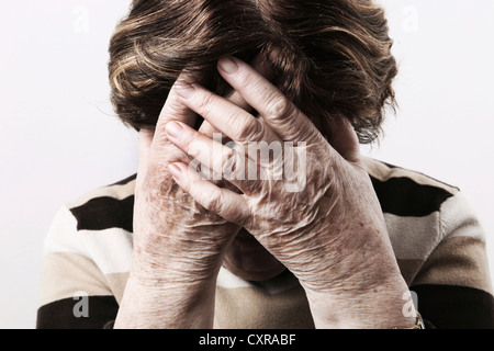Donna anziana alla ricerca angosciata e tenendo le sue mani sul viso Foto Stock