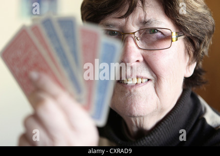 Donna anziana tenendo le carte da gioco in mano Foto Stock