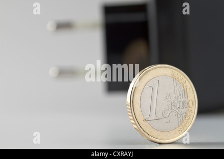 Un euro-moneta e una spina di alimentazione sul retro, immagine simbolica per tassi di elettricità Foto Stock