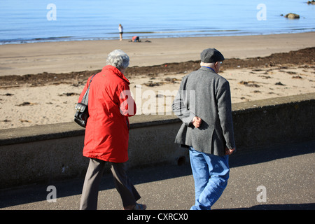 Coppia di anziani a piedi lungo la passeggiata nella cittadina balneare di Girvanin Ayrshire in Scozia Foto Stock