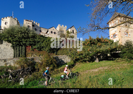 Paio di equitazione biciclette elettriche passato il castello di Castelbello, Tschars, provincia di Bolzano, Italia, Europa Foto Stock