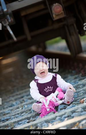 Ragazza, 1, seduti sui binari della ferrovia e pianto Foto Stock